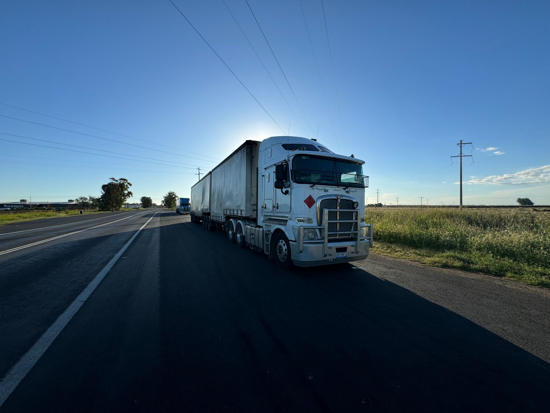 Prime mover and trailer on a rural Australian highway at sunrise